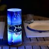 Lamp shown in an outdoor dining scene at night providing a dramatic center piece for guests.