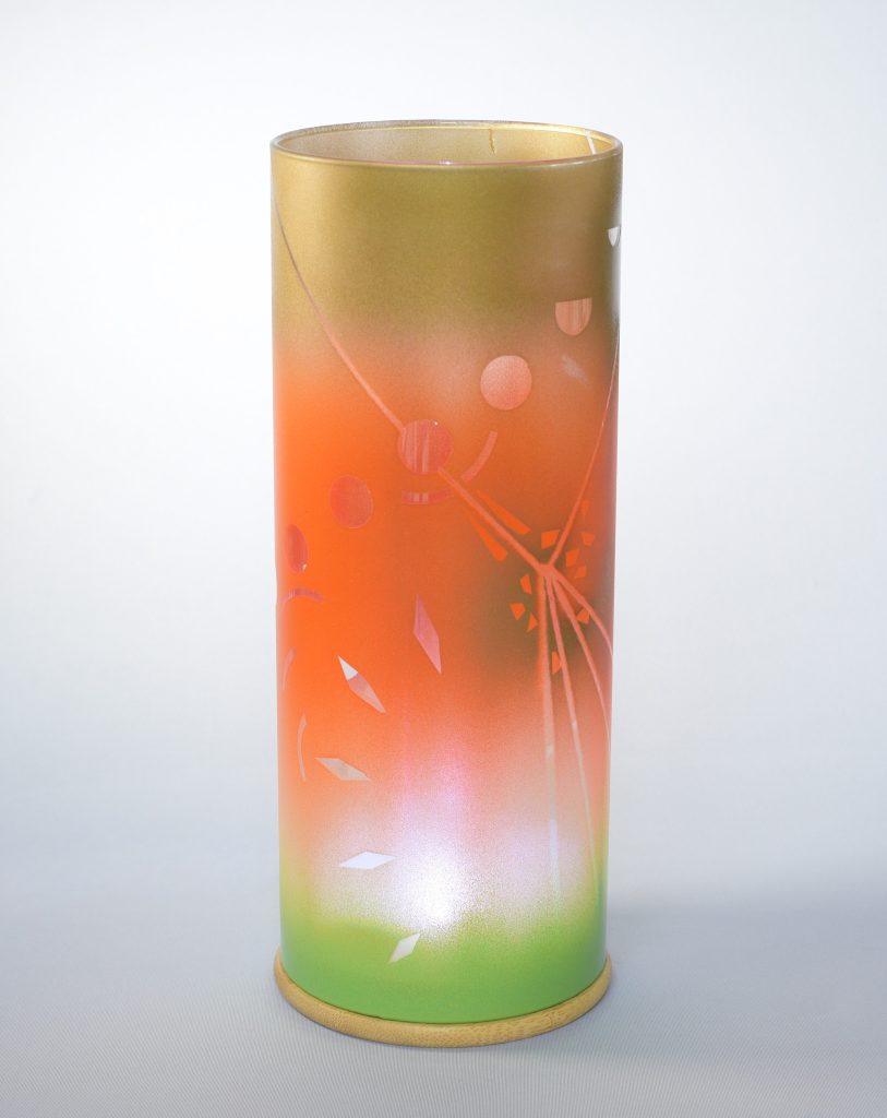 Art glass lamp shown against flood lit backdrop displaying face view.
