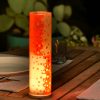 Lamp shown in an outdoor dining scene at night providing a dramatic center piece for guests.