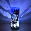 Shown on a display shelf with its LED illuminated, lamp displays brilliant patterns of light on projected surface.