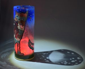 Shown under spot light at upper left, lamp displays brilliant projected color and shadow patterns. Highlighted are displays of patterns through clear glass.