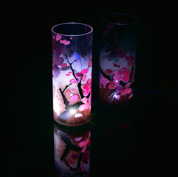 Lit only by its LED, lamp shown with reflective black plexiglass below and at the lamp’s side. Lamp displays duel brilliant mirrored images.