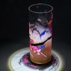 Lamp shown under spot light set directly overhead. Photo displays marvelous projected patterns of light and shadow surrounding base of lamp. Also displayed is the transparency of the glass cylinder.