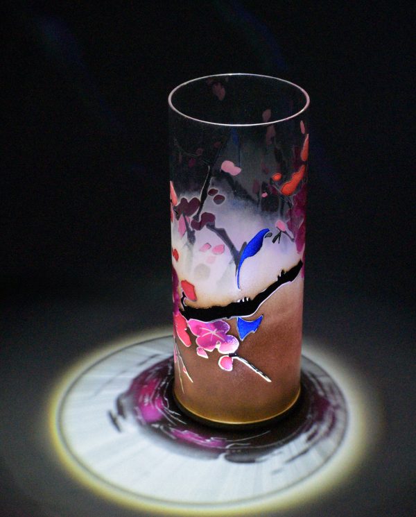 Lamp shown under spot light set directly overhead. Photo displays marvelous projected patterns of light and shadow surrounding base of lamp. Also displayed is the transparency of the glass cylinder.