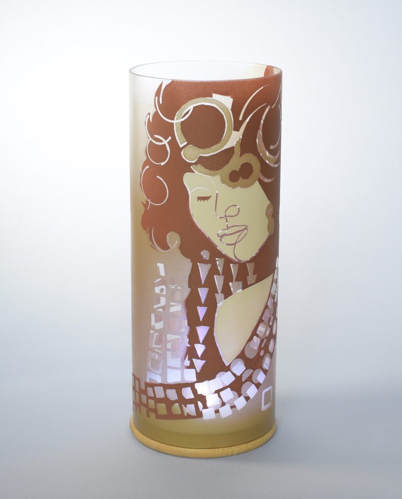 Art glass lamp shown against flood lit backdrop displaying face view.