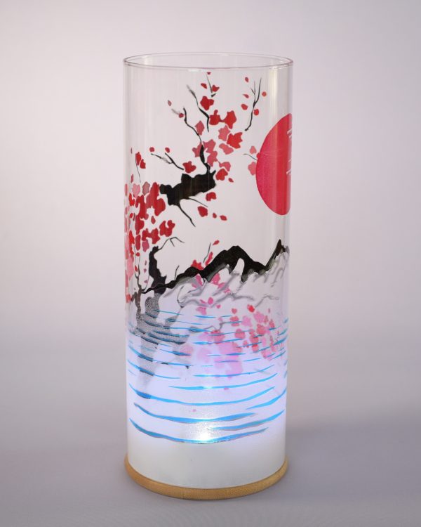 Unique art glass lamp shown against flood lit backdrop displaying mountain view.