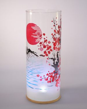 Unique art glass lamp shown against flood lit backdrop displaying face view.