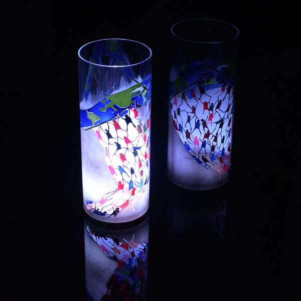 Anje Rozan unique art glass lamp shown placed on, and beside reflective black plexiglass while lit only by its internal LED. Lamp displays duel brilliant mirrored images.