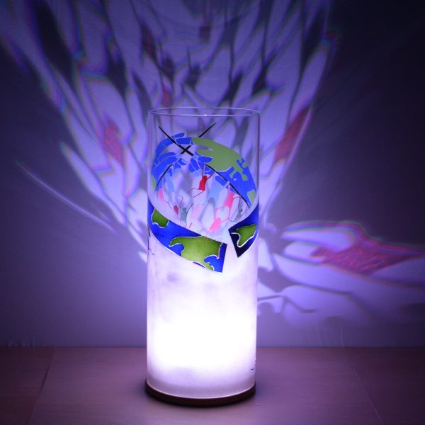 Anje Rozan shown with only LED illuminated. Unique art glass lamp displays brilliant color patterns on backdrop.