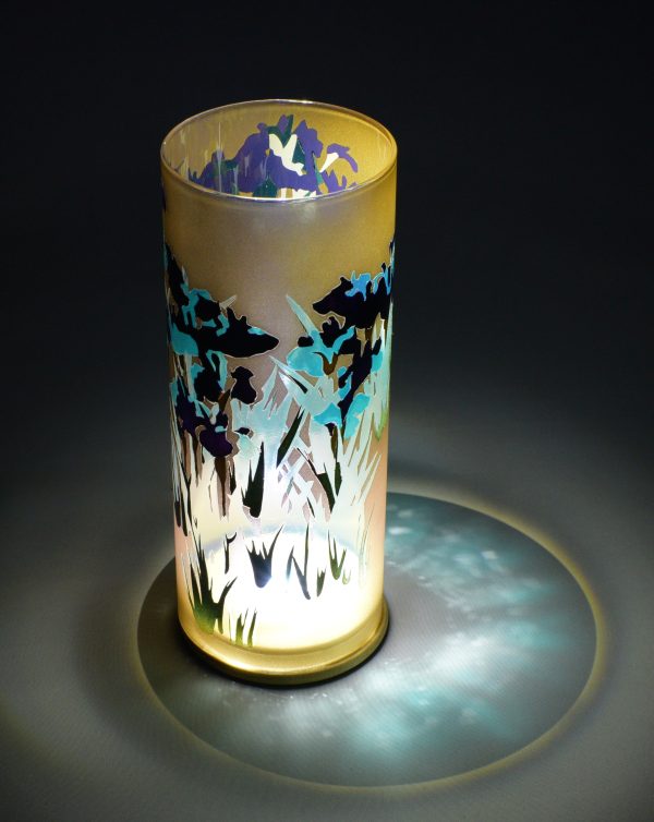 Art glass lamp shown under spot light set directly overhead. Photo displays marvelous projected patterns encircling base of lamp.