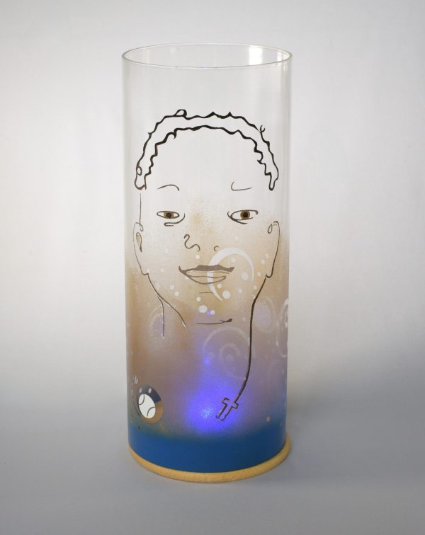 Unique art glass lamp shown against flood lit backdrop displaying face view.