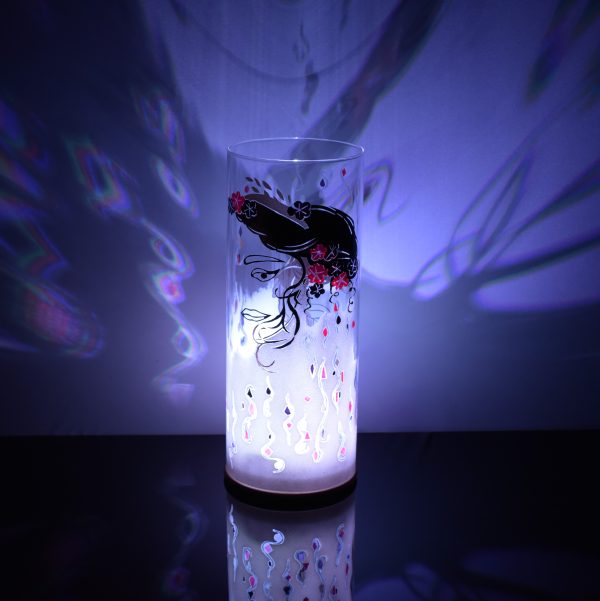 Art glass lamp shown placed on reflective black plexiglass while lit only by its internal LED. Lamp brilliant projected image.