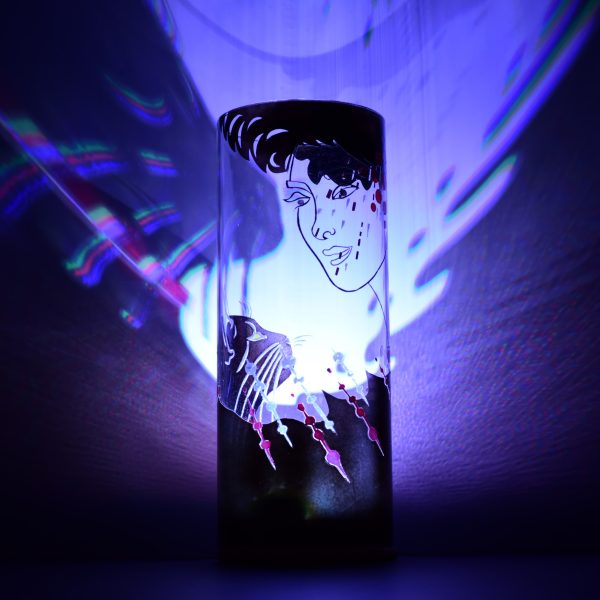 Shown with only LED illuminated. Unique art glass lamp displays brilliant color patterns on backdrop.