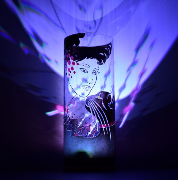 Shown with only LED illuminated. Unique art glass lamp displays brilliant color patterns on backdrop.