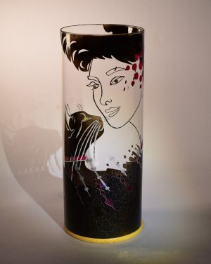 Art glass lamp shown against flood lit backdrop displaying face view.