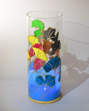 Art glass lamp shown against flood lit backdrop displaying front view.